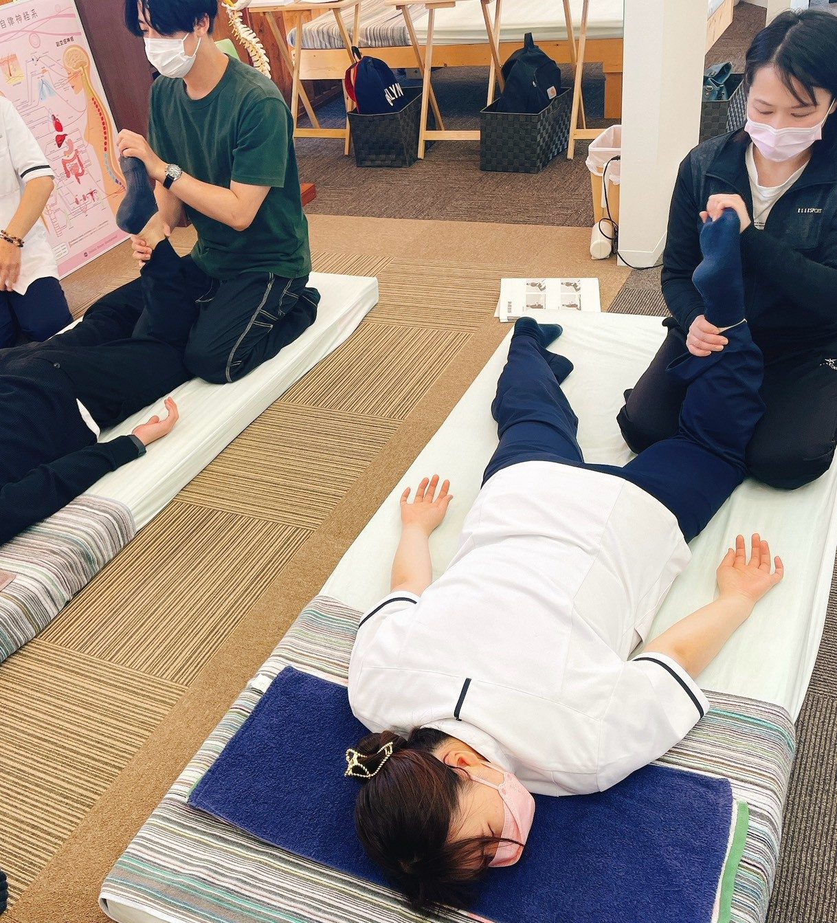 実技講習の様子。複数の受講者がペアになり、マットの上で手技を練習している